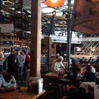Restaurant, medium crowd, on side of big room, sports tv football match in the background, cutlery, beeping, dishes, London, UK