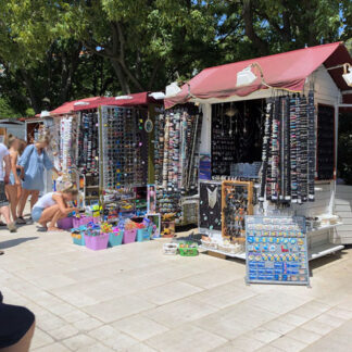 Port, tourists, market stalls, wind chime made of shells, tourists, distant motorboat, Krk, Croatia