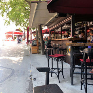 Bar near port, noon time, glasses, small crowd, distant large crowd on square, traffic, summer feeling, Krk, Croatia